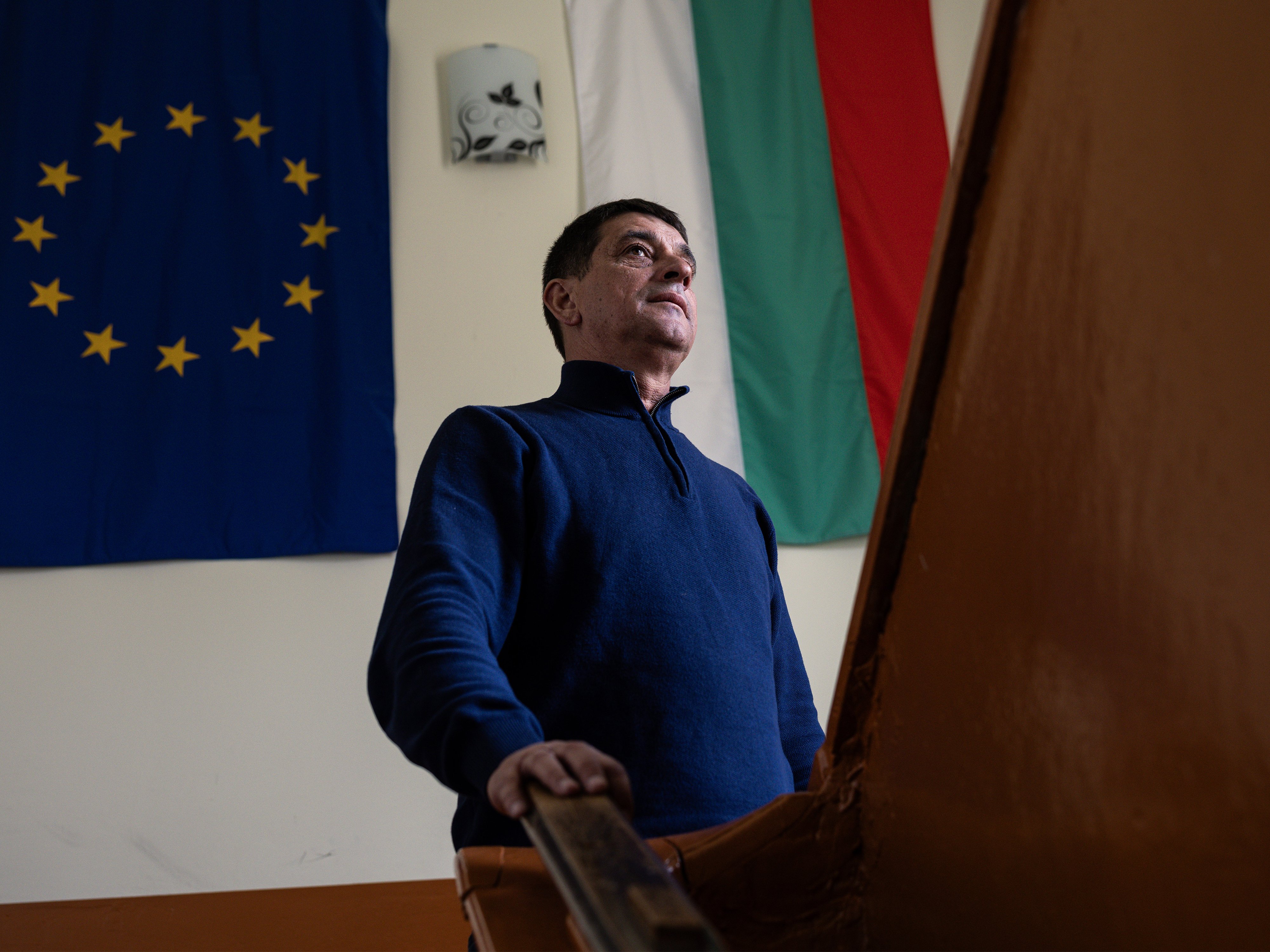 A man on the stairs at a Bulgarian school, with the EU and Bulgarian flags visible behind him. Photo: Akos Stiller